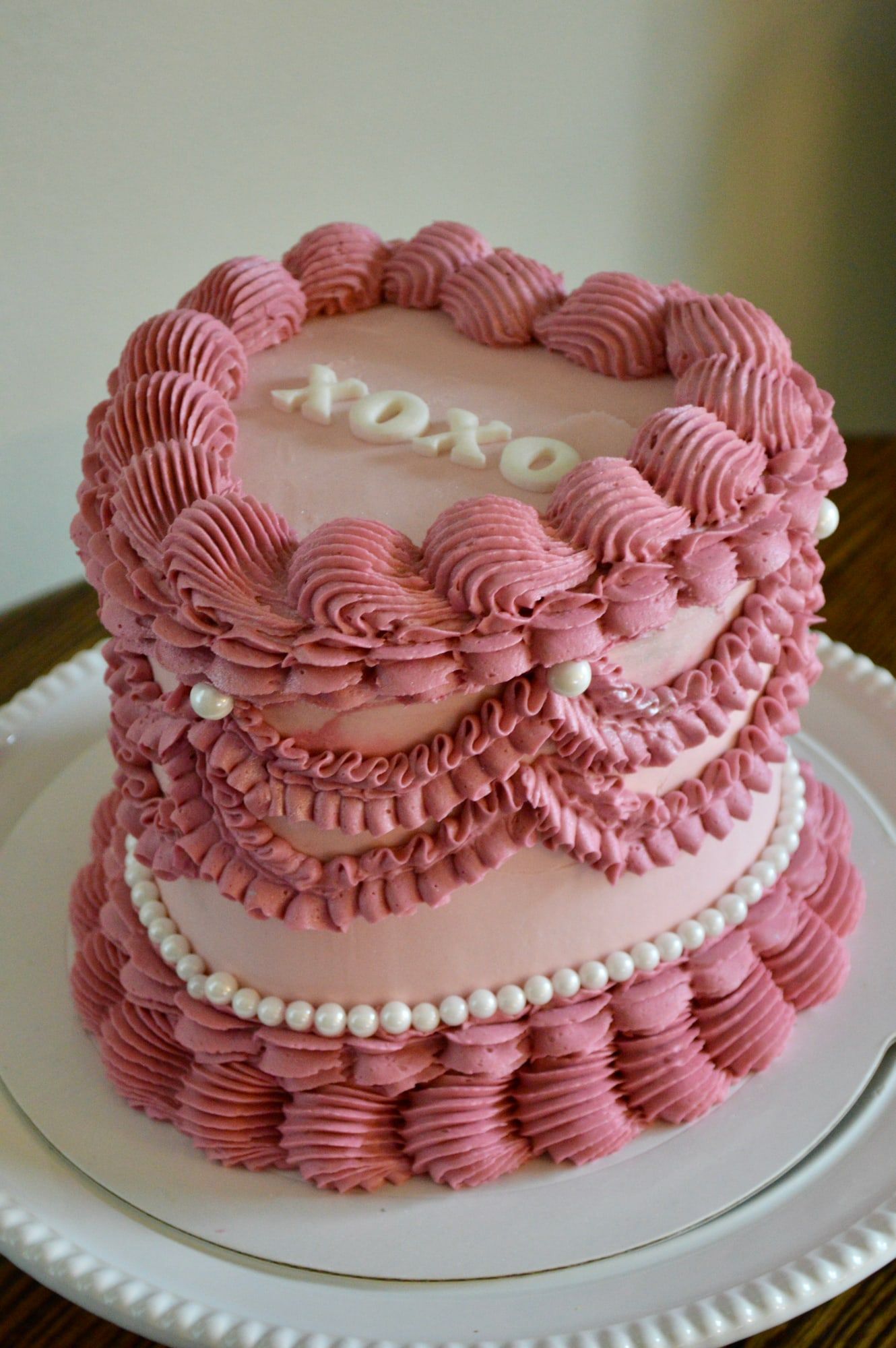 Dusty pink cake in vintage piping style with ruffles, pearls and XOXO lettering