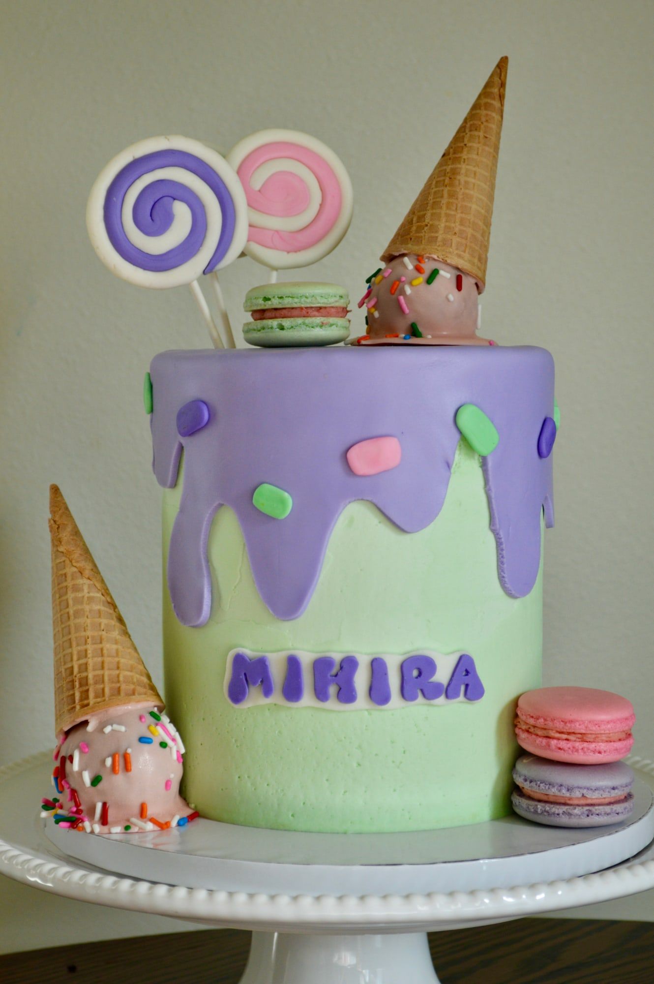 Pastel green and lilac birthday cake with a lilac drip, ice cream cones and macarons