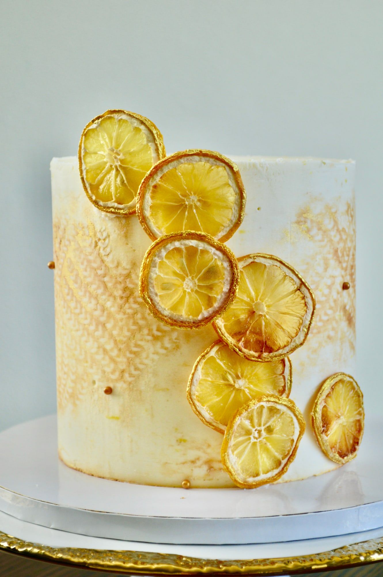 Textured white buttercream cake trimmed with candied lemon slices and gold leaf
