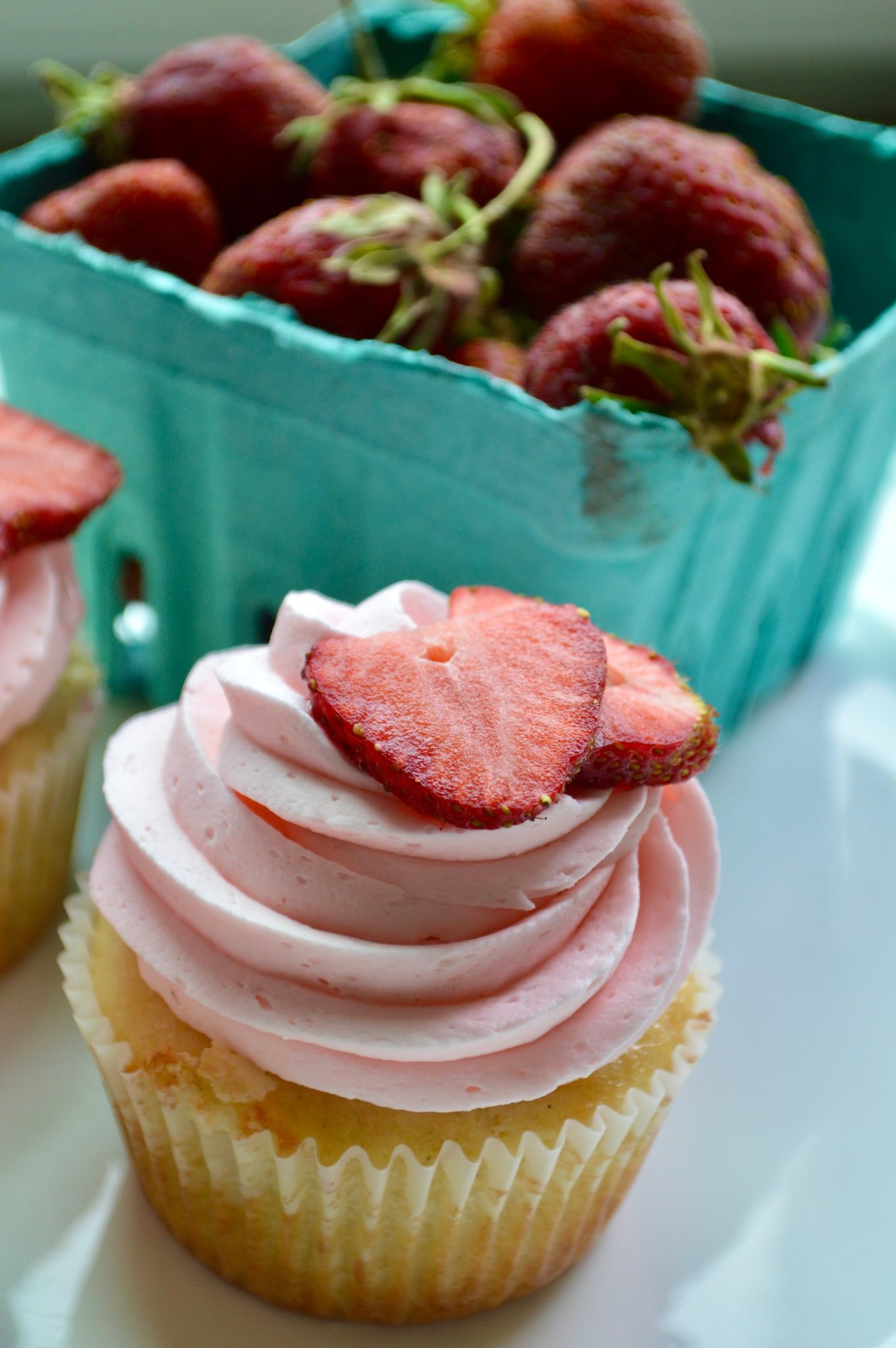 Strawberry cupcake topped with pink buttercream and a fresh strawberry slice