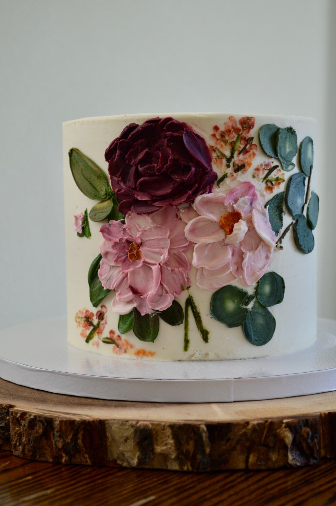 White buttercream cake hand-painted with burgundy and blush garden flowers and eucalyptus