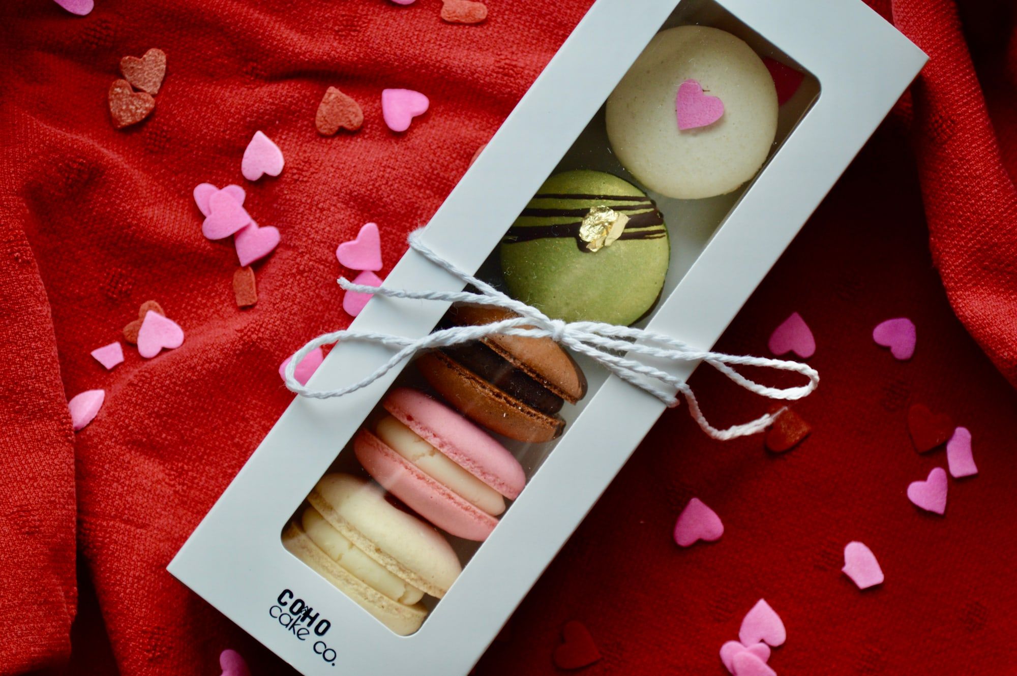 A Coho Cake Co. gift box of assorted macarons tied with twine