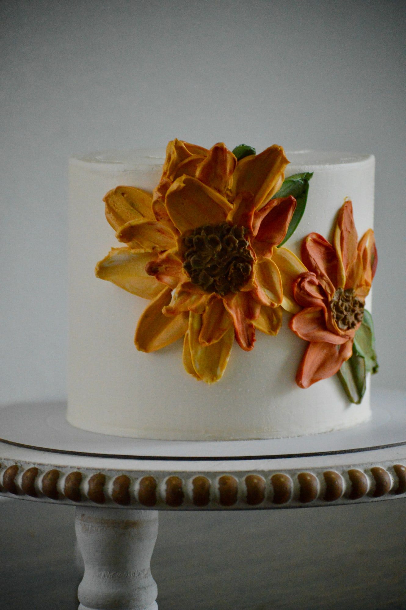 White buttercream cake with hand-piped sunflowers in gold and rust